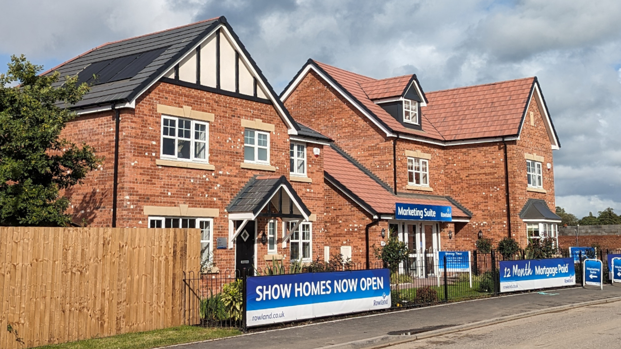 A showhome with a sign in front which reads show home now open.